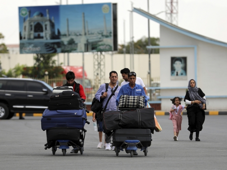 На фото: пассажиры идут к терминалу вылета международного аэропорта имени Хамида Карзая в Кабуле, Афганистан, 14 августа 2021 года.