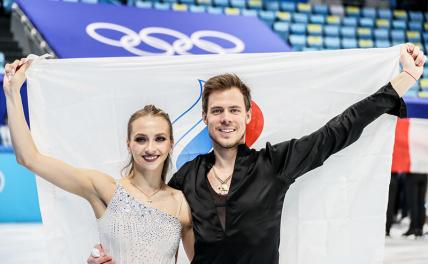 На фото: Виктория Синицина и Никита Кацалапов (ОКР, серебряные медали) во время цветочной церемонии.