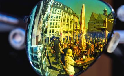 На фото: посетители ресторана под открытым небом на Рёмерберге, Франкфурт-на-Майне, отражаются в стекле солнцезащитных очков.