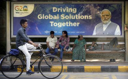На фото: велосипедист проезжает мимо автобусной остановки с плакатом премьер-министра Индии Нарендры Моди перед предстоящим на этой неделе саммитом Большой двадцатки в Нью-Дели, Индия