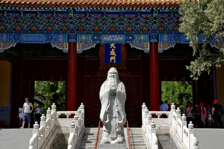 На фото: туристы проходят мимо статуи древнего китайского философа Конфуция во время посещения храма Конфуция в Пекине, Китай.