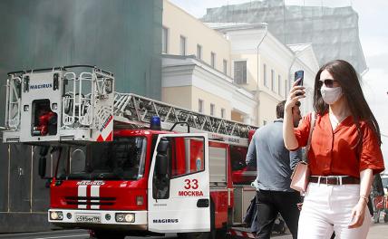 На фото: люди возле здания на Большой Никитской улице, где произошло возгорание.