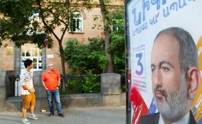 На фото: предвыборный плакат с изображением исполняющего обязанности премьер-министра Армении Николом Пашиняном рядом с избирательным участком.