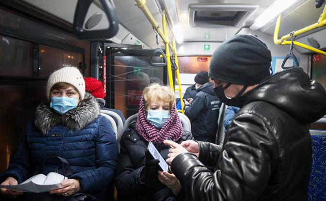 На фото: сотрудник контрольно-ревизионной службы во время проверки QR-кодов у пассажиров в автобусе на остановке общественного транспорта.