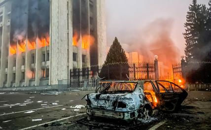 На фото: сгоревший автомобиль возле горящего здания акимата, Алма-Ата, Казахстан.