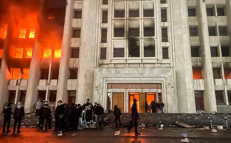 На фото: протестующие возле горящего здания акимата. Участники протеста против роста цен на топливо ворвались в здание акимата и пожодгли его.