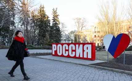 На фото: женщина у надписи "Россия" на улице города. Глава ДНР Денис Пушилин обратился к президенту РФ Владимиру Путину о признании независимости республики ДНР.