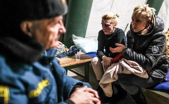 На фото: сотрудник МЧС и эвакуированные жители Мариуполя в лагере МЧС.