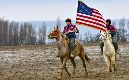 На фото: товарищи по команде США по кок-бору едут на лошадях с национальным флагом во время товарищеского матча во время чемпионата по кок-бору в честь 30-летия дипломатических отношений между Кыргызстаном и США на ипподроме Чолпон-Ата, 250 км (155 миль)