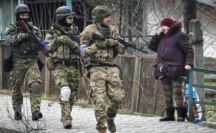 На фото: украинские военнослужащие и местная жительница на одной из улиц города Буча.