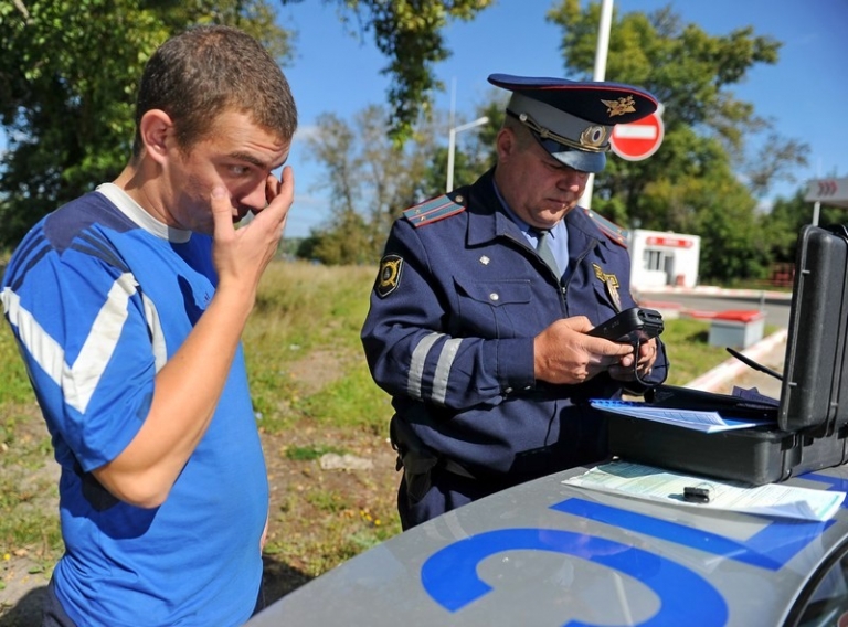 На фото: сотрудник ГИБДД проверяет водителя автомобиля алкотестером на содержание алкоголя в крови во время рейда по выявлению нарушителей