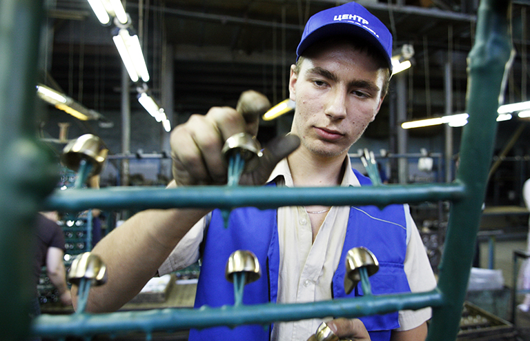 На фото: школьник работает на заводе по выпуску сантехнического оборудования.