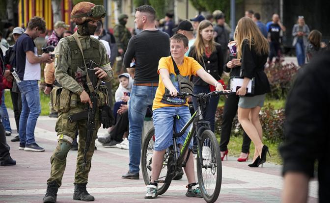 На фото: российский военнослужащий и местные жители Мелитополя.