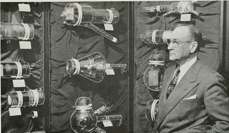 На фото: инженер-электрик и изобретатель Владимир К. Зворыкин стоит перед дисплеем некоторых из изобретенных им исторических телевизионных ламп. Работая в лабораториях Westinghouse и RCA с 1923 по 1940-е годы, Зворыкин изобрел первые успешные телевизионные системы с электронным сканированием, в том числе широко используемый тубус камеры-иконоскопа.