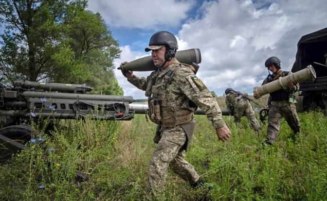 На фото: украинский военнослужащий несет 155-мм артиллерийский снаряд