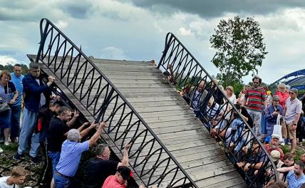 На фото: люди во время обрушения пешеходного моста на фольклорном фестивале "Ольгины берега", Луга, Ленинградская область.