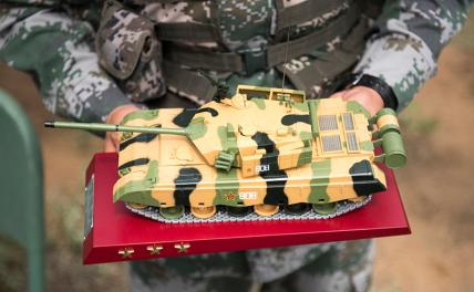 На фото: китайский солдат НОАК представляет модель основного боевого танка ZTZ99.