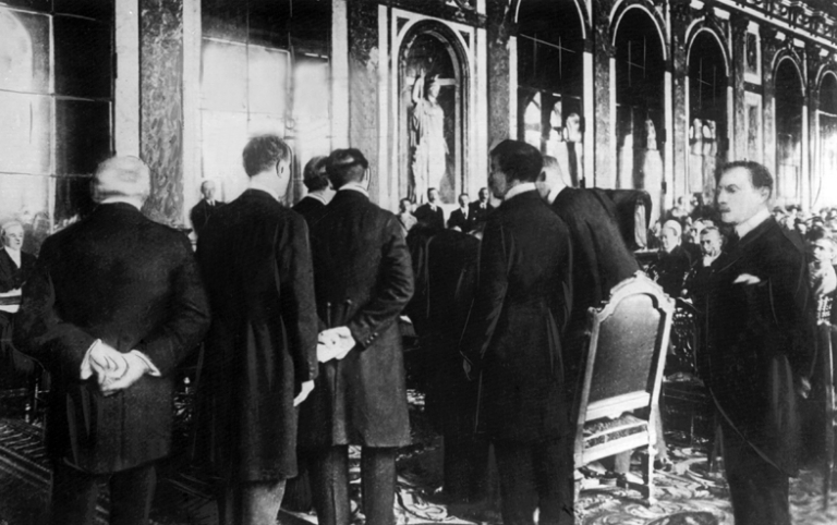 На фото: Герман Мюллер (справа) подписывает Версальский договор в качестве министра иностранных дел. За ним Йоханнес Белл, 1919 год.