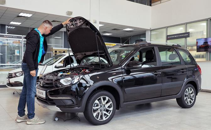 На фото: посетитель автосалона во время осмотра автомобиля Lada Granta.