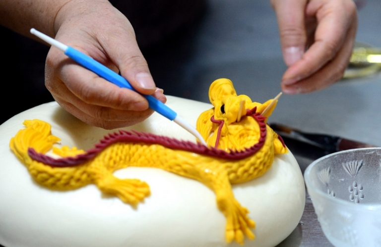 На фото: приготовление паровых булочек с изображением драконов к Новому году по лунному календарю в Китае.