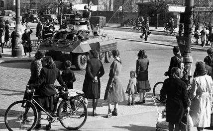 На фото: жители Берлина в зоне США смотрят на проезжающие по улице американские полицейские войска, 1945 год.