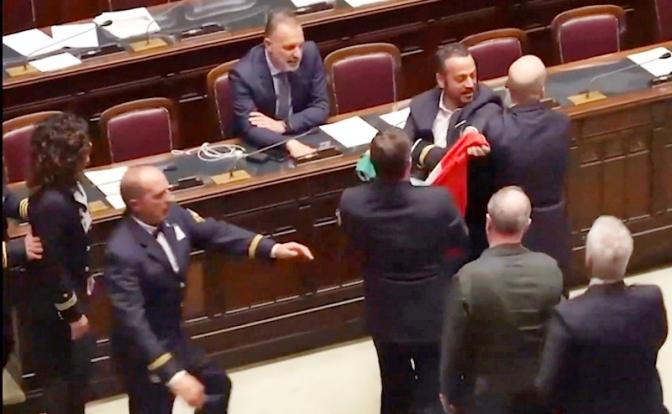 На фото: политик Леонардо Донно оказывается на земле после того, как его ударил член Северной Лиги Иззи во время протеста в Палате против дифференцированной автономии. Донно пытался передать Кальдероли итальянский флаг.