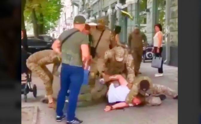 На фото: сотрудники украинского военкомата отлавливают молодого отца на улице.