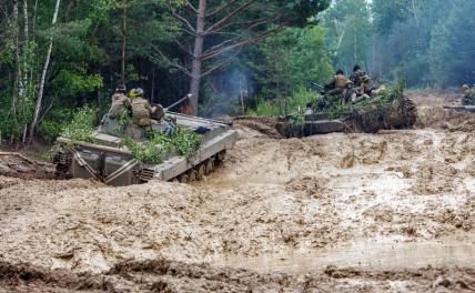 На фото: украинские солдаты едут на БМП по размытой дождем дороге