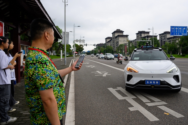 На фото: представитель зарубежных китайских СМИ готовится к поездке на Apollo Go Robotaxi, автономной платформе для заказа такси от Baidu в Чунцине, Китай.