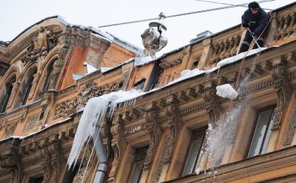 На фото: Санкт-Петербург. Сотрудники коммунальной службы счищают лед и снег с крыши дома