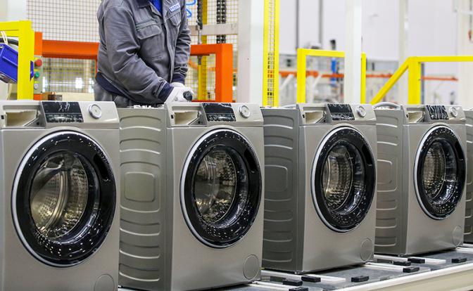На фото: сотрудник сборочного конвейера на заводе стиральных машин Haier
