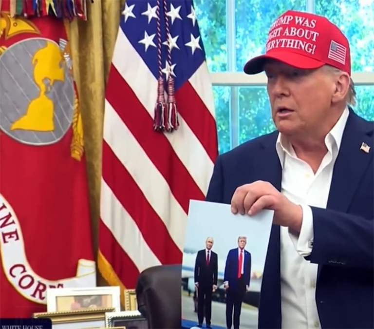 На фото: Трамп показывает фотографию с Путиным журналистам.