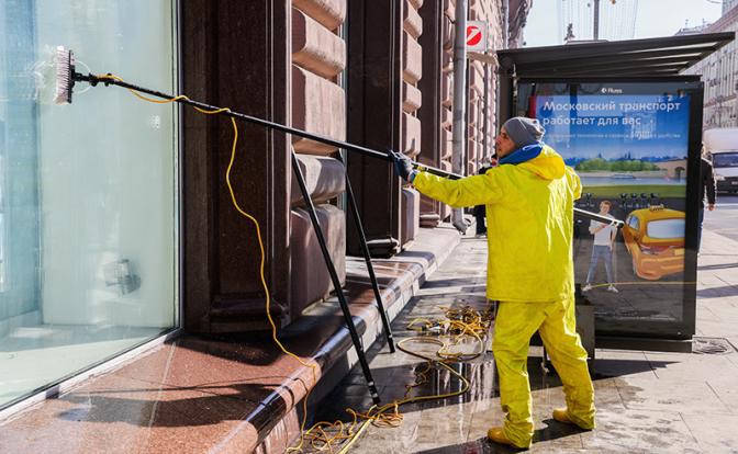 На фото: индивидуальный предприниматель моет окна на одной из улиц Москвы.