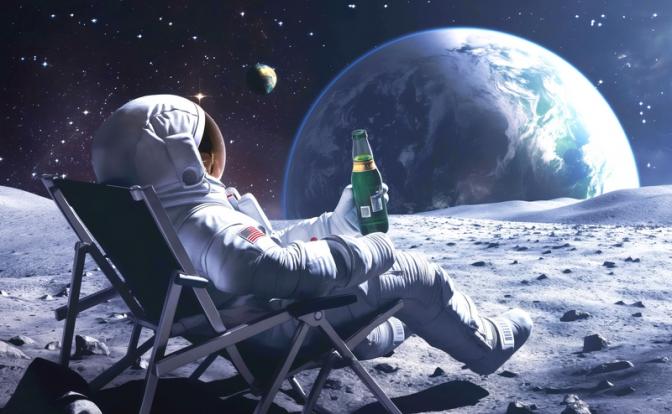 На фото: астронавт, сидящий в раскладном кресле на лунной поверхности с напитком в руке и наблюдающий за Землей.