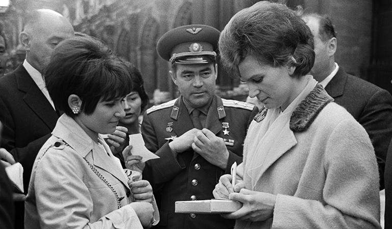 На фото: летчики-космонавты СССР Андриян Григорьевич Николаев (в центре) и Валентина Владимировна Николаева-Терешкова (справа) во время раздачи автографов жителям города, 1965