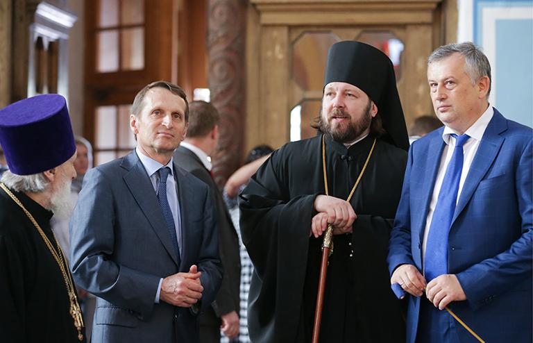 На фото: спикер Госдумы РФ Сергей Нарышкин (второй слева), епископ Гатчинский и Лужский Митрофан (в центре) и губернатор Ленинградской области Александр Дрозденко (справа) во время посещения Покровского храма в Гатчине, 2016