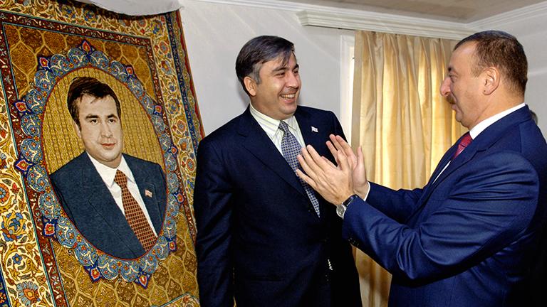 На фото: президенты Грузии и Азербайджана Михаил Саакашвили и Ильхам Алиев (слева направо) перед началом церемонии открытия грузинского участка нефтепровода Баку-Тбилиси-Джейхан (БТД). Президент Азербайджана подарил Михаилу Саакашвили ковер, на котором изображен его портрет, 2005 год