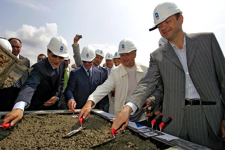 На фото: вице-премьер правительства РФ Александр Жуков, официальный представитель Президента в Южном федеральном округе Дмитрий Козак, президент ОКР Леонид Тягачев и губернатор Краснодарского края Александр Ткачев (слева направо на первом плане) во время торжественной церемонии заливки первого кубометра бетона в основание будущей олимпийской деревни в Имеретинской долине, 2006 год